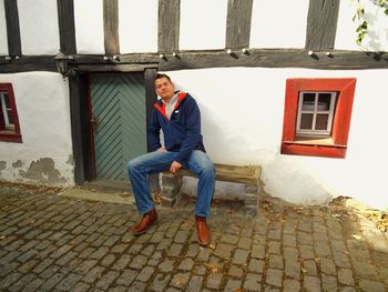 Full length portrait of smiling man sitting outdoors