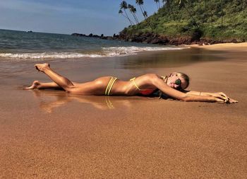 Woman lying on beach against sky