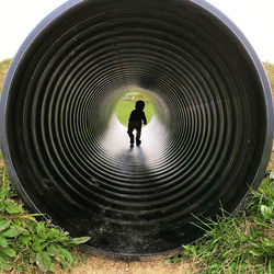 Rear view of silhouette man standing in tunnel