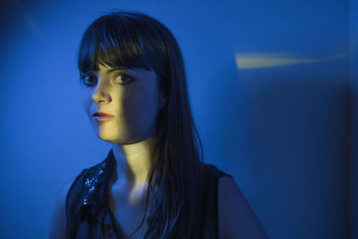 Portrait of young woman against blue background