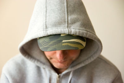 Close-up of man in hoodie standing against wall