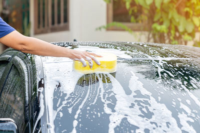 Hands hold yellow sponge for washing car at home. holiday hobby.