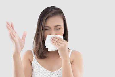 Woman sneezing against white background