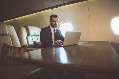 Businessman using laptop on table in air vehicle
