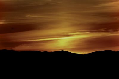 Scenic view of silhouette mountains against orange sky