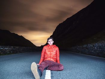 Portrait of man sitting on road against mountain