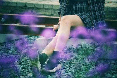 Low section of woman sitting on railroad track outdoors