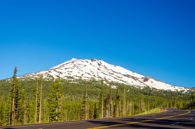 Empty road by mt bachelor against clear blue sky