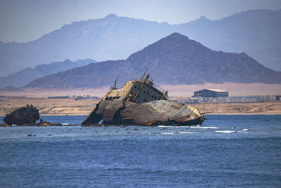 Sailboat on sea by mountains against sky