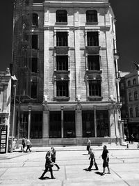 People walking on street against building in city