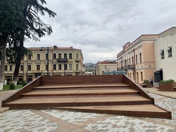 Footpath amidst buildings in city against sky