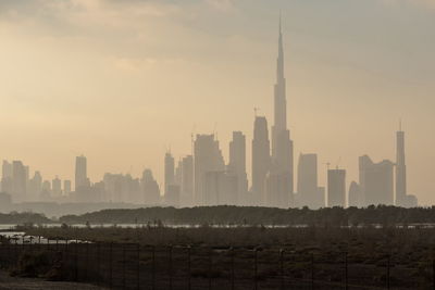 Buildings in city against sky during sunset