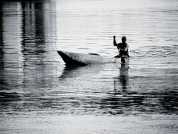 Reflection of man in boat on lake