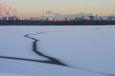 Frozen lake against sky during sunset