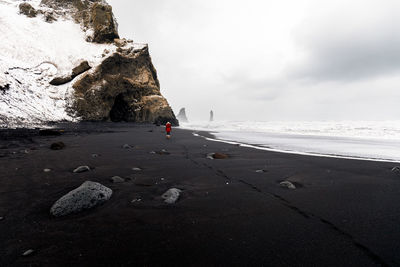 People on rock at beach against sky