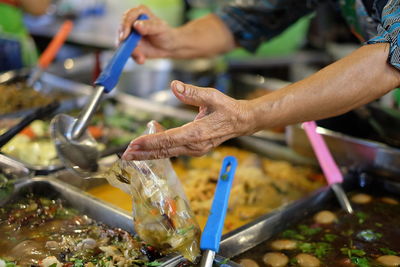 Cropped hands of vendor packing food