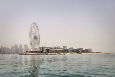 Ferris wheel and buildings in city against clear sky