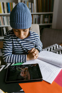 Boy communicating with teacher at homeschooling class in living room