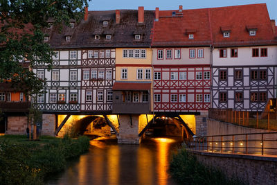 Arch bridge over river amidst buildings in city