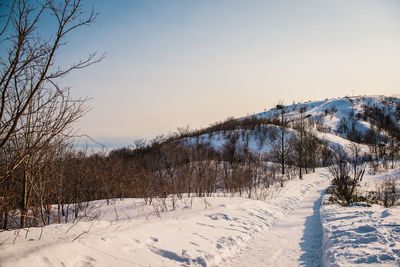 Snow covered land against sky during sunset