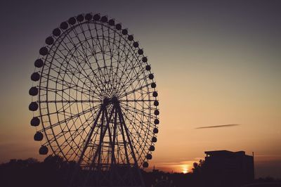 Low angle view of ferris wheel against sky at sunset