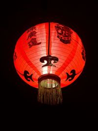 Low angle view of illuminated lantern hanging against black background