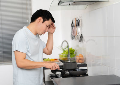 Side view of young woman preparing food at home