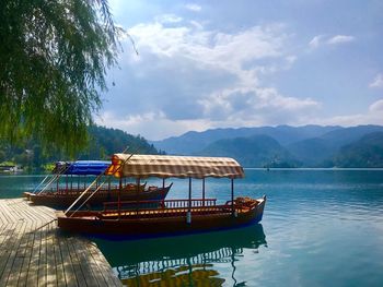 Boat moored on lake against sky