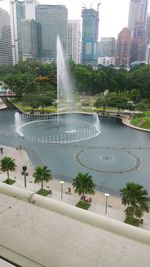 Fountain in city against modern buildings