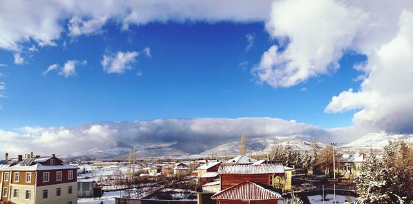 Buildings in town against cloudy sky