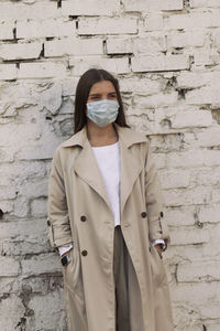 Portrait of young woman standing against wall