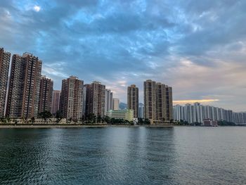 Sea by modern buildings against sky in city