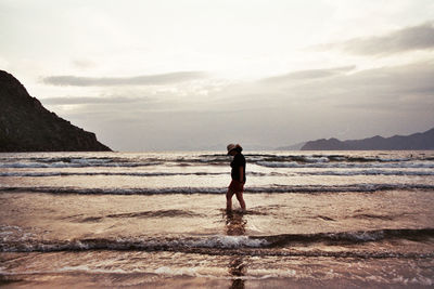 Full length of man standing on beach against sky