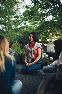 Mid adult woman sitting with eyes closed by friends in balcony during group session