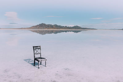 Empty chair on beach against sky