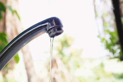 Close-up of water flowing from faucet against blurred background
