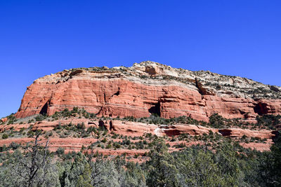 Low angle view of rock formations against clear blue sky