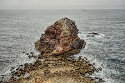 Rock formation on sea shore against sky