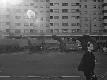 Rear view of man walking on street against buildings in city