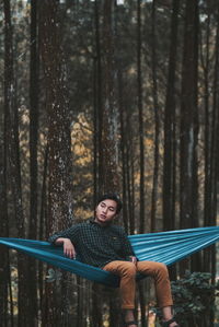 Young woman sitting on tree trunk in forest