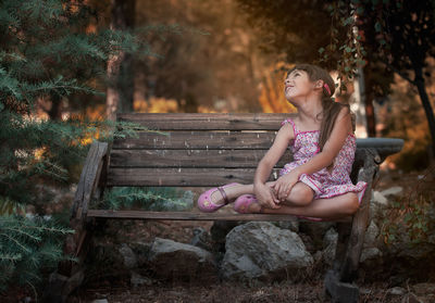 Girl looking away while sitting on bench