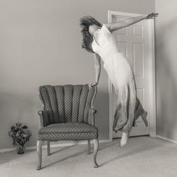 Woman dancing on floor by chair at home