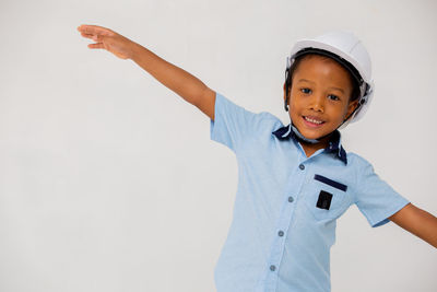 Portrait of smiling boy standing against white background