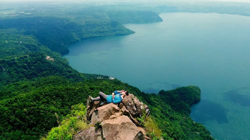 High angle view of woman lying on cliff against sea