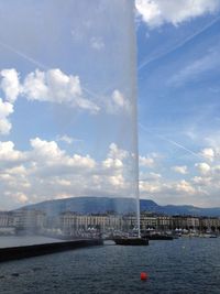 City at waterfront against cloudy sky