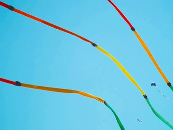 Low angle view of flags hanging against clear blue sky