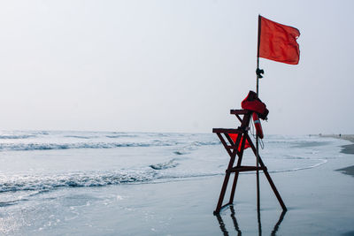 Red umbrella on snow covered land against sky