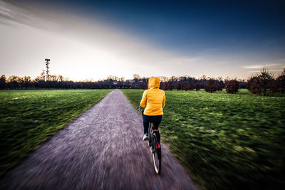 Rear view of woman riding bicycle on road