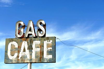 Low angle view of sign against blue sky