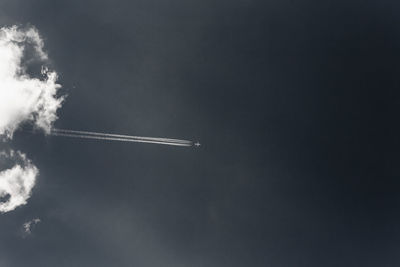 Low angle view of airplane with vapor trails flying against sky